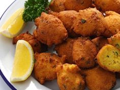 fried food on a plate with lemon wedges and parsley