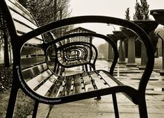 a black and white photo of a bench on a rainy day with no one in it