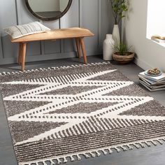 a white and brown area rug with tassels on the floor in front of a mirror