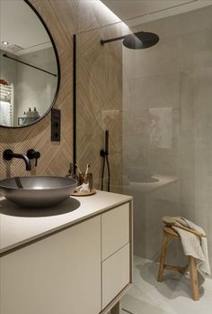 a bathroom with a sink, mirror and stool in the shower area next to it