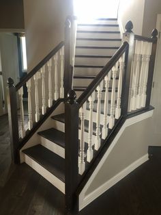 a staircase with white railing and black handrails