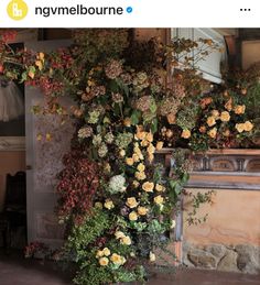 flowers are growing up the side of a fireplace