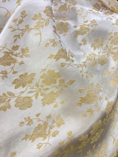 a white and gold fabric with flowers on it