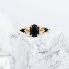 a black and white diamond ring sitting on top of a marble block with two diamonds