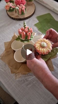 someone is decorating small flower arrangements on a table