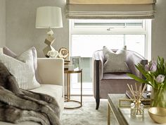 a living room filled with furniture next to a window covered in blinds and flowers on top of a coffee table