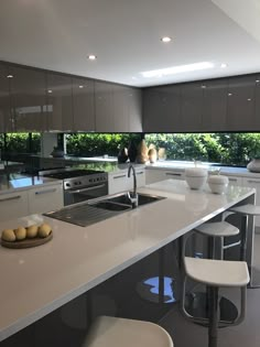 a kitchen with white counter tops and stools next to an island in the middle