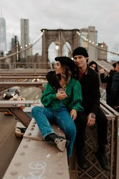 a man and woman sitting on top of a bridge