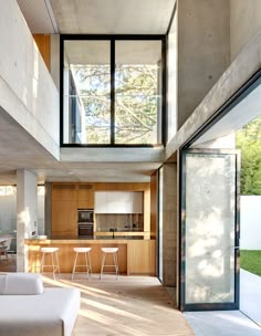 an open kitchen and living room area in a modern house with large windows on the ceiling