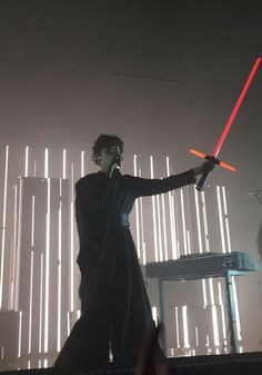 a man with a light saber in his hand standing next to a keyboard on stage