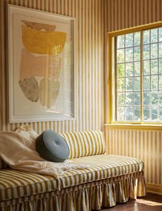 a room with striped wallpaper and a bench in front of a window that has a painting on the wall