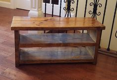 a wooden table sitting on top of a hard wood floor next to a stair case