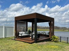 a wooden gazebo sitting on top of a lush green field next to a lake