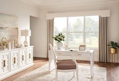 a white desk and chair in front of a large window with curtains on the windowsill