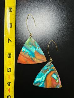 a pair of earrings sitting next to a measuring tape