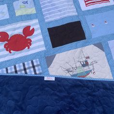 a quilted wall hanging on the side of a bed covered in blue and white fabric