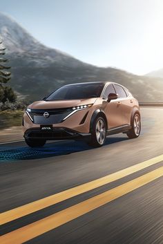 an electric car driving down the road with mountains in the background