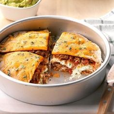 a pan filled with meat and cheese pastries next to a bowl of guacamole