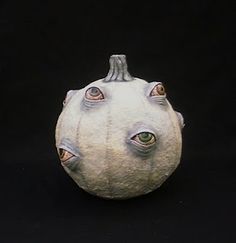 a white pumpkin with two eyes on it's face and an eyeball in the middle