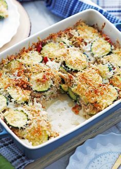 a casserole dish with zucchini, cheese and other toppings in it