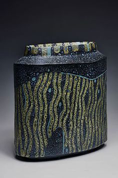 a black and yellow vase with designs on the outside, inside it's lid