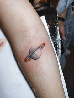 a small saturn tattoo on the arm