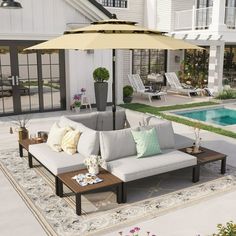 an outdoor living area with couches, table and umbrella