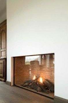 a fire place in the middle of a living room with wood floors and white walls