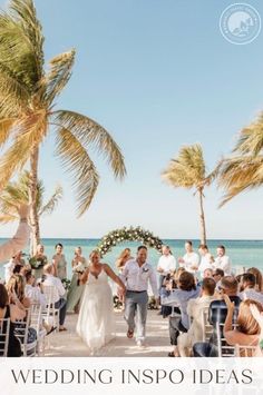 a bride and groom walking down the aisle to their wedding ceremony on the beach with palm trees