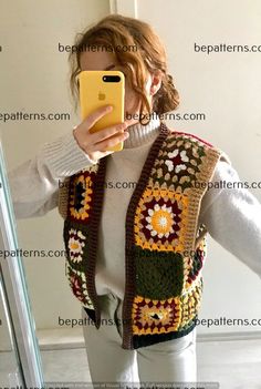 a woman taking a selfie in front of a mirror wearing a crocheted vest