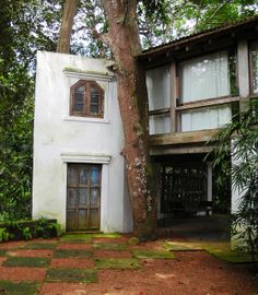 an old house with a tree in front of it and a stone walkway leading to the door