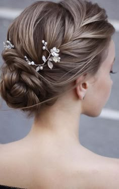 a woman wearing a wedding hair comb with flowers in her hair, looking off to the side