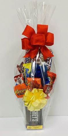 the candy gift basket is wrapped in cellophane and tied with a red bow