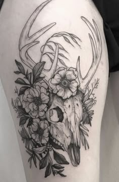 a black and white photo of a deer skull with flowers on it's thigh