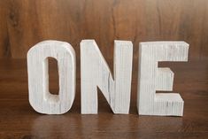 the word one is made out of wooden letters on a table with a wood background