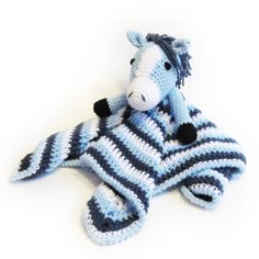 a crocheted stuffed horse laying on top of a blue and white striped blanket