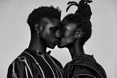 two black women are kissing each other in front of a white background and one is wearing an afro hairstyle