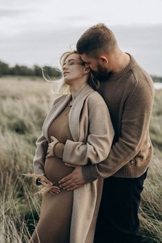 a pregnant couple standing in tall grass