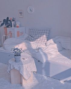 a bed with white sheets and pillows in a room filled with plants on the floor