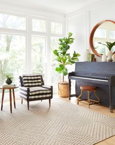 a living room with a piano, chair and table in front of large windows on the wall