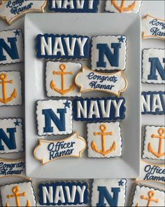 decorated cookies are arranged on a plate with navy letters and an anchor in the center