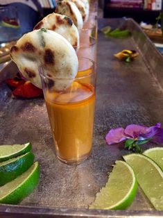 some food is sitting in a glass on a tray next to limes and flowers