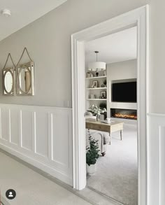 an open door leading to a living room with white walls and carpeted flooring