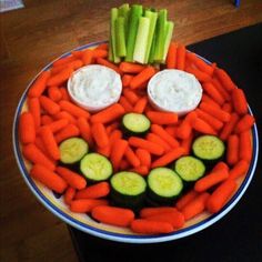 a plate with carrots, celery and cucumbers arranged to look like a face