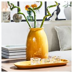 a yellow vase filled with flowers sitting on top of a table next to two glasses