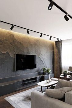 a living room with couches and a flat screen tv mounted to the side of a wall