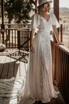 a woman in a white dress and hat standing on a porch