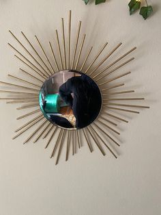 a sunburst shaped mirror hanging on the wall next to a vase with flowers