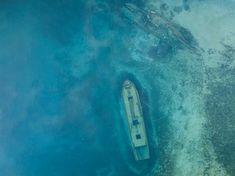 an aerial view of a small boat in the middle of the ocean with another boat nearby