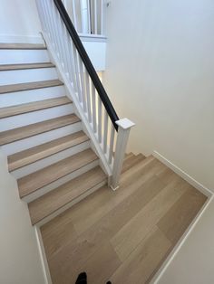 there is a pair of black shoes on the wooden floor next to the stair case